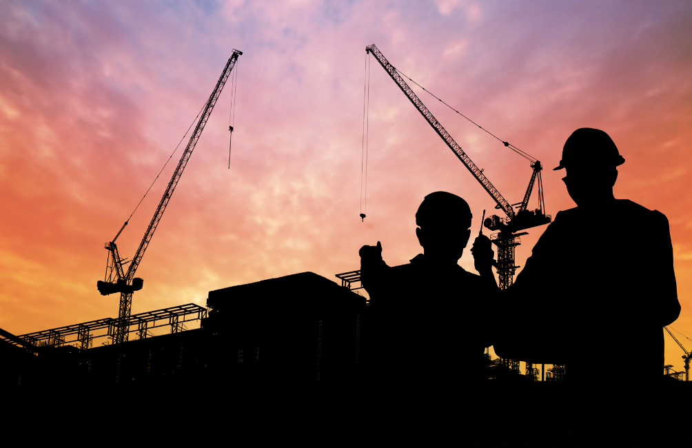 Silhouette of two engineers surveying a Scottish grid construction site at sunset, symbolising planning, teamwork, and the energy infrastructure project.
