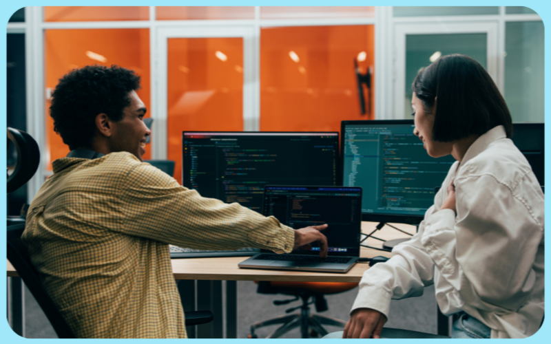 Vallum consultants reviewing a project on a computer, based on contract staffing solutions across global markets.