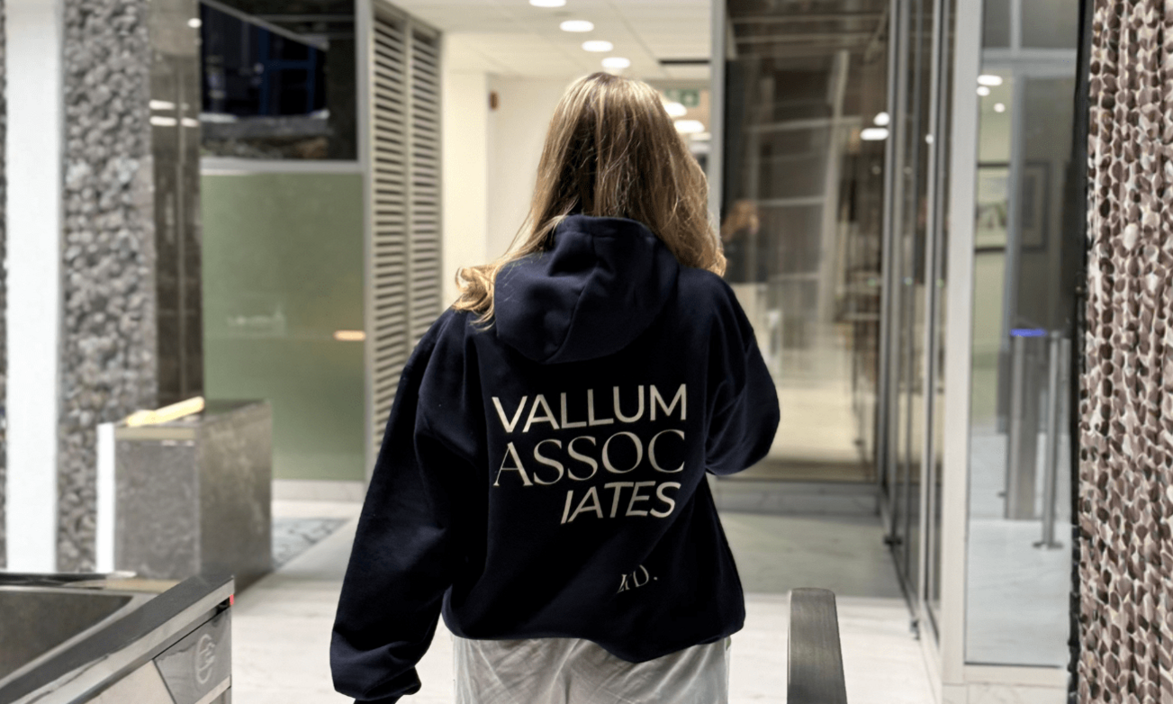 Vallum Associates Employee wearing a hoodie with "Vallum Associates LTD" on the back walking away from camera into a bright and modern office